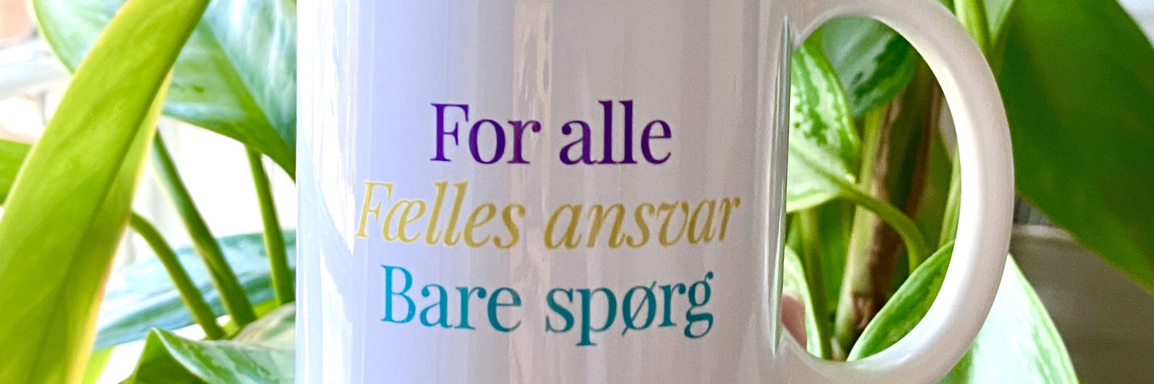 billede af kop med Byens hus motto for alle/fælles ansvar/bare spørg
